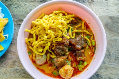 Khao Soi, Khao Soi Kai, Thai Noodles Khao Soi, ahşap zeminde baharatlı körili tavuk, Kuzey Tayland yemeği konsepti. (Lanna yemeği)