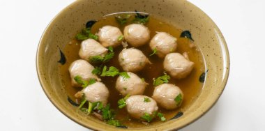 Domuz köfteli erişte çorbası, ahşap masada.