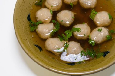 Domuz köfteli erişte çorbası, ahşap masada.