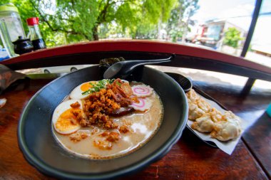 Erişte, domuz eti, tavuk, haşlanmış yumurta ve deniz yosunu salatasıyla servis edilen sebze tabakları.
