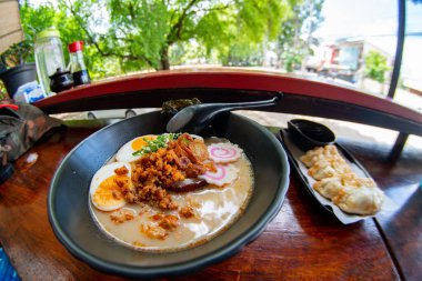 Erişte, domuz eti, tavuk, haşlanmış yumurta ve deniz yosunu salatasıyla servis edilen sebze tabakları.