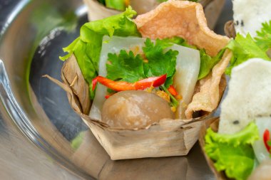 Domuz eti ve fıstık dolgulu buğulanmış tapyoka (Sago) topları, ünlü geleneksel Tayland aperatifi / sokak yemekleri Saku Sai Moo, sebze ve biberle servis edilir. Sago İncisi ya da Tapyoka İncisi