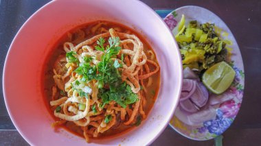 Khao Soi, Khao Soi Kai, Thai Noodles Khao Soi, ahşap zeminde baharatlı körili tavuk, Kuzey Tayland yemeği konsepti. (Lanna yemeği)