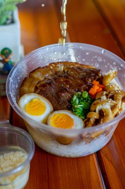 a bowl of rice topped with chashu pork and seasoned boiled egg clipart