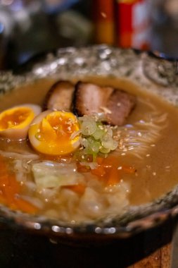 Sapporo ramen eriştesi siyah arka planda buharlı kırmızı çubuklarla kaldırıldı.