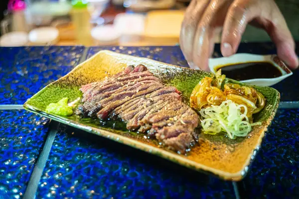 Biftek ızgarasında ince dilimler halinde et kızarmaya ve cızırdamaya başlıyor, otantik Japon restoranı.