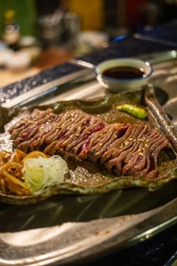 Biftek ızgarasında ince dilimler halinde et kızarmaya ve cızırdamaya başlıyor, otantik Japon restoranı.
