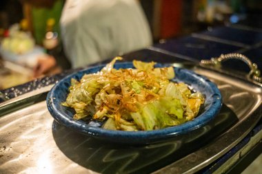 Yeşil çimen arka planında Japon kasesinde balık soslu kızarmış lahana, Asya ev yapımı yemek konsepti..