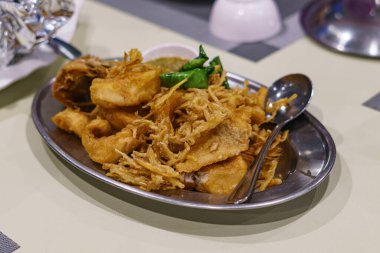 Yakından ve yukarıdan bakıldığında, beyaz seramik tabakta bitkilerle kızartılmış Tilapia. Popüler Tayland yemekleri