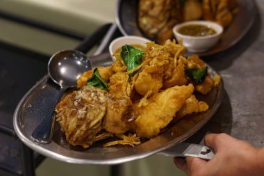 Yakından ve yukarıdan bakıldığında, beyaz seramik tabakta bitkilerle kızartılmış Tilapia. Popüler Tayland yemekleri