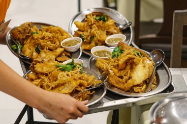 Yakından ve yukarıdan bakıldığında, beyaz seramik tabakta bitkilerle kızartılmış Tilapia. Popüler Tayland yemekleri