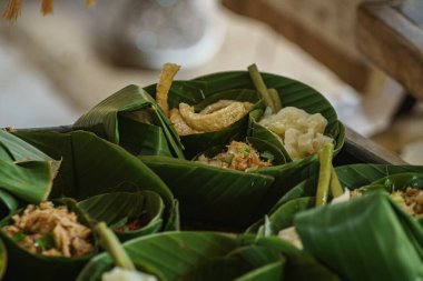 Geleneksel Tayland yemeklerini eko-dost muz yaprağı kaplarında sunan güzel bir resim. Her porsiyon dilimlenmiş et, otlar ve kırmızı biber karışımı içeriyor., 