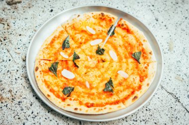 Metal bir tabaktan erimiş peynirli, jambonlu ve domates soslu taze pişmiş bir pizza alan birinin yakın çekimi. Yapışkan peynir esnemesi ve lezzetli detayları yakalamak için mükemmel bir zaman..