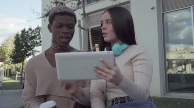 Üniversitenin kampüsündeki tablet üzerinde iki genç üniversite öğrencisinin değerlendirme notları var..