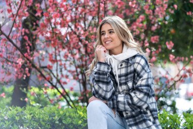 Arka planda çiçekleri olan beyaz bir kadın.