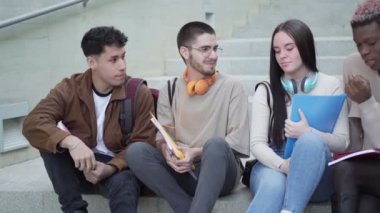 multi-ethnic group of students, take a break sitting on the stairs of the university campus.