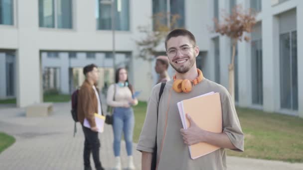 Estudiante Mirando Cámara Mientras Sus Amigos Están Detrás Hablar Campus — Vídeos de Stock