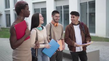 a group of college students are standing on the college campus talking about exams.