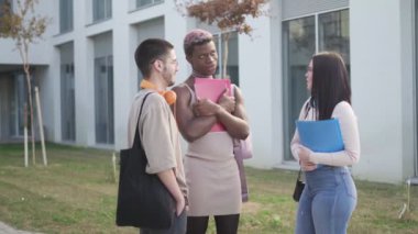 a group of college students are standing on the college campus talking about exams.