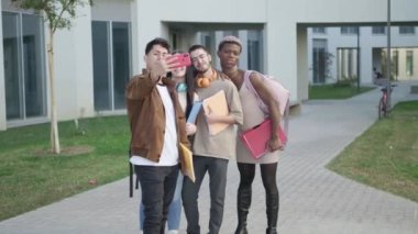 Bir grup üniversite öğrencisi, üniversite kampüsünde akıllı telefonlarıyla selfie çekiyor..