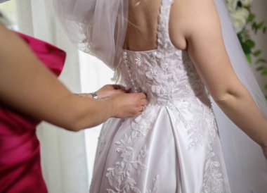 Nedime gelinliği bağlıyor. Genç bir gelin seremoniden önce fermuarını çeker.