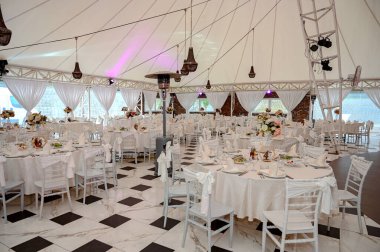 Sandalyeler ve masa çiçeklerle süslenmiş çatal bıçaklar ve çanak çömlekle servis edilmiş ve masa örtüsüyle örtülmüş. Özel düğün konsepti