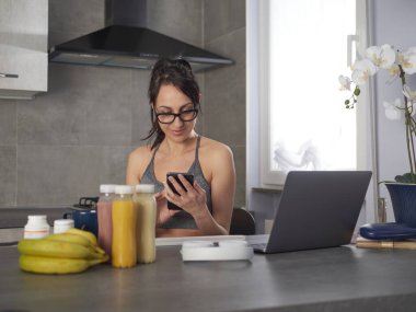 Şirin, güzel ve mutlu esmer kadın mutfakta meyve ya da sağlıklı bir içecek hazırlıyor ve eğleniyor.