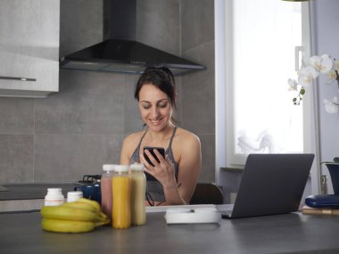 Şirin, güzel ve mutlu esmer kadın mutfakta meyve ya da sağlıklı bir içecek hazırlıyor ve eğleniyor.