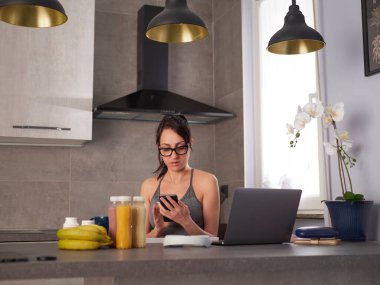 Şirin, güzel ve mutlu esmer kadın mutfakta meyve ya da sağlıklı bir içecek hazırlıyor ve eğleniyor.