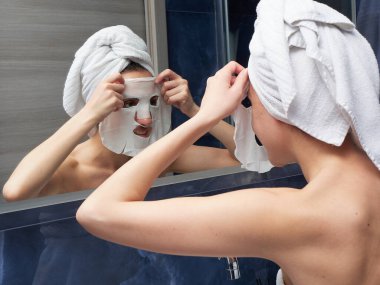 Kadın yüz maskesini banyoya koymuş.