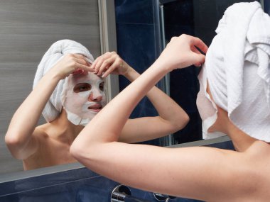 Kadın yüz maskesini banyoya koymuş.