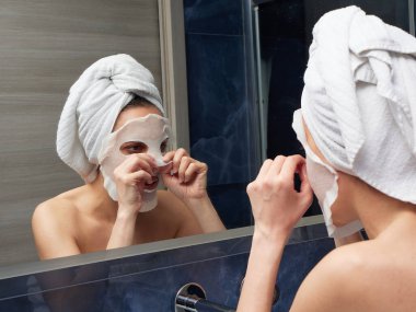 Kadın yüz maskesini banyoya koymuş.