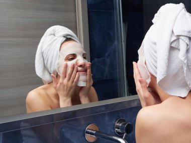 Kadın yüz maskesini banyoya koymuş.