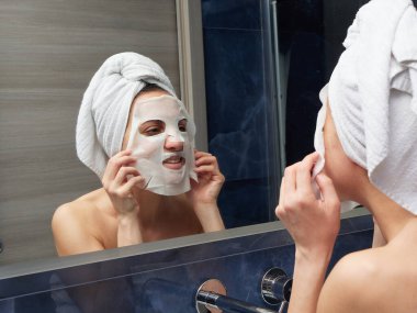 Kadın yüz maskesini banyoya koymuş.