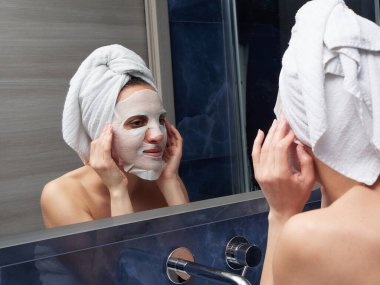 Kadın yüz maskesini banyoya koymuş.