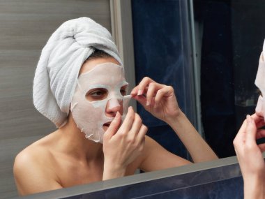 Kadın yüz maskesini banyoya koymuş.