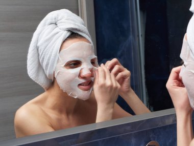 Kadın yüz maskesini banyoya koymuş.