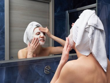 Kadın yüz maskesini banyoya koymuş.