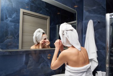 Kadın yüz maskesini banyoya koymuş.