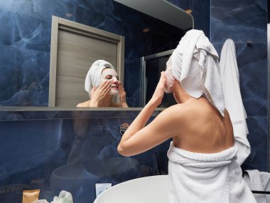 Kadın yüz maskesini banyoya koymuş.