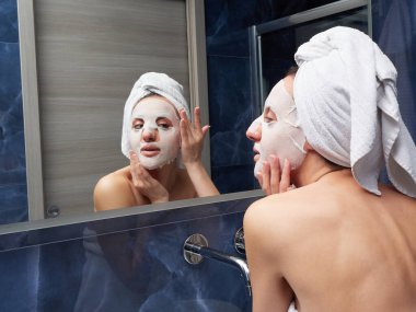 Kadın yüz maskesini banyoya koymuş.