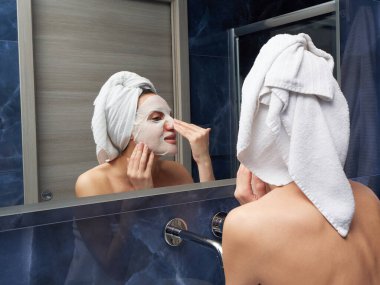 Kadın yüz maskesini banyoya koymuş.