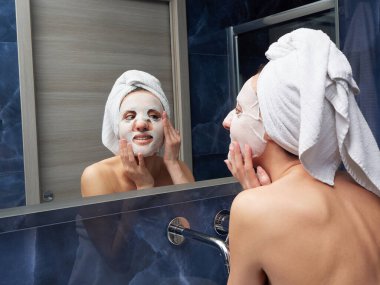 Kadın yüz maskesini banyoya koymuş.