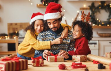 Mutlu Afro-Amerikan aile babası ve çocukları Noel hediyelerini paketliyor.