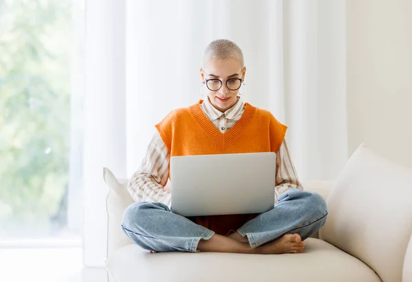 머리로 안경을 아름다운 프리랜서의 소파에 앉아서 집에서 일하는 노트북으로 일하는 — 스톡 사진