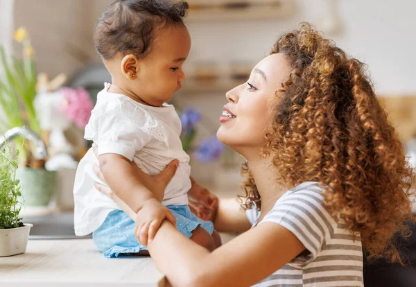 幸せで明るいアフリカ系アメリカ人の母親は 彼女の腕の中に笑いの赤ちゃんの娘を保持しています 母親と家族の愛の概念 — ストック写真