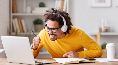 Başarı ve başarı. Genç neşeli Afro-Amerikalı adam dizüstü bilgisayara heyecanla bakıyor e-posta ya da sınav sonucu iş teklifi aldıktan sonra heyecanlanıyor.