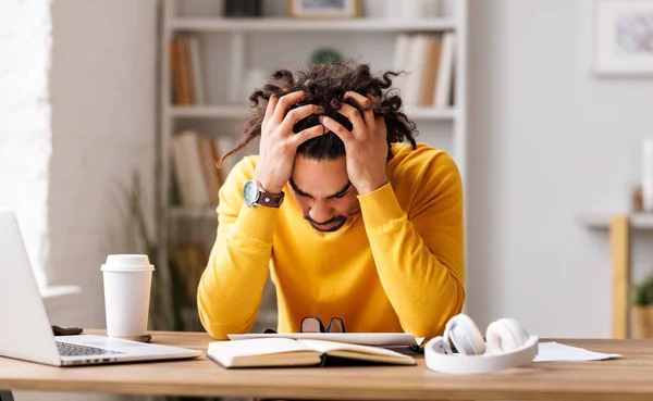 stock image Frustrated tired young african american entrepreneur with closed eyes massages temples with fingers with painful expression on her face, sitting in front of laptop  working remotely online. Frustrated black guy has computer problem