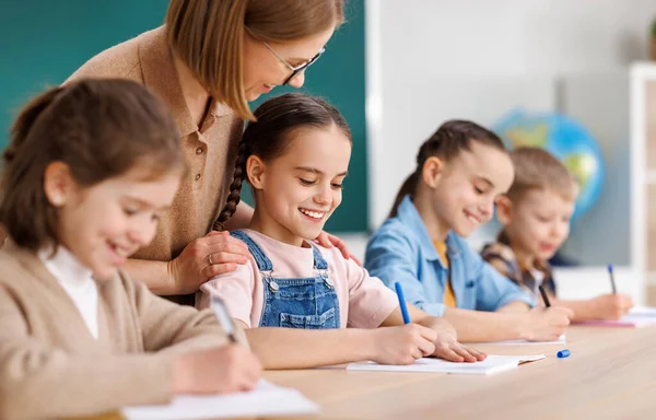 Friendly Woman Glasses Smiling Supporting Smart Children Fulfilling Assignment Table — Stock Photo, Image