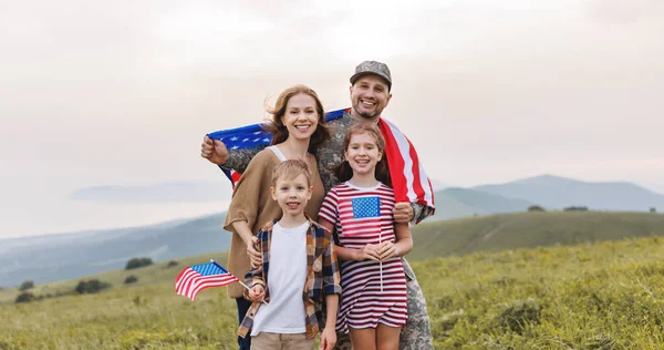 Military homecoming. Young military man soldier happy to be reunited with his patriotic family,  wife and two kids with American flags meeting father from US army on july 4th